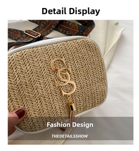 Detail of woven straw bag with gold logo, tassel charm, and floral wide strap