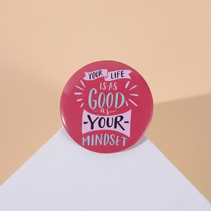 Detail of rose pink tinplate badge with Your Life Is As Good As Your Mindset quote