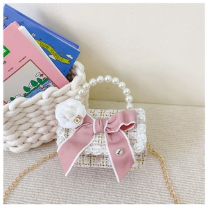 Detailed texture of pink tweed girls handbag with pearl handle and bow decoration