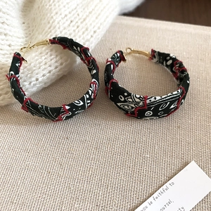 Détail de créoles avec imprimé bandana et finitions de couture rouges faites à la main