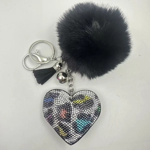 Detail of black plush ball keychain with a colorful rhinestone leopard heart and silver tassel