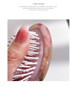Close-up of flexible pink marble hairbrush cushion demonstrating airbag massage effect