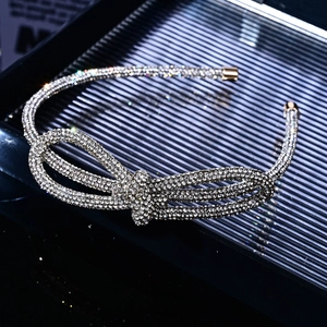 Macro detail of a silver rhinestone bow headband with shiny metallic finish