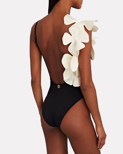 Detail of 3D white floral applique and gold metal logo on black backless swimsuit