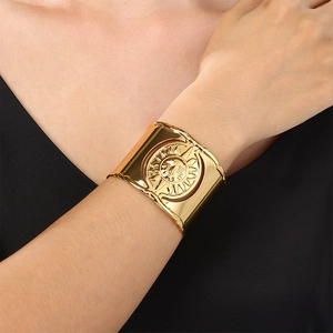 Close-up of gold wide cuff bracelet featuring a sun emblem and ripple texture