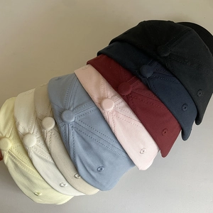 Multiple colors of cotton baseball caps with embroidered eyelets stacked in a minimalist style