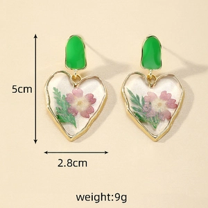 Detail view of heart-shaped green dried flower resin earrings with size 5cm by 2.8cm