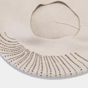 Vue détaillée du béret en maille beige montrant la texture fine et les strass brillants