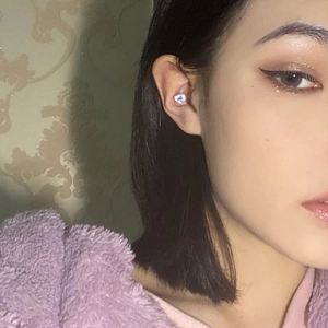 Detail shot of a small purple zircon magnetic earring worn on the ear conch area