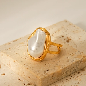 Bague perle baroque française en acier inoxydable doré sur un socle en pierre beige