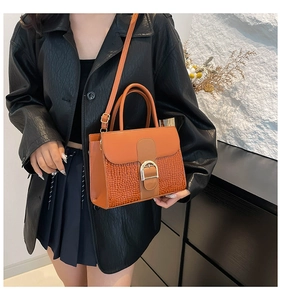 Détail du cuir texturé crocodile sur le sac à main marron orange avec boucle