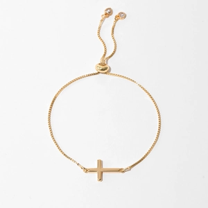Detail of gold box chain bracelet featuring a polished cross and adjustable sliding clasp