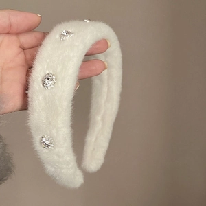 Close-up of a plush white headband adorned with large sparkling crystal rhinestones