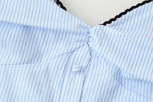 Detailaufnahme des blau gestreiften Kleidausschnitts mit schwarzer Spitze und Knopf