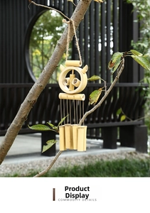 Bamboo wind chime with owl design hanging on a tree branch in a zen garden setting