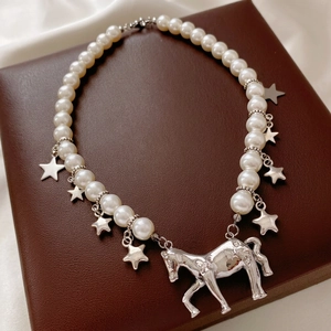 Elegant pearl necklace with silver star and pony pendants on dark leather background