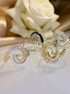 Macro detail of spiral zircon rings in gold and silver finish with white oil drip