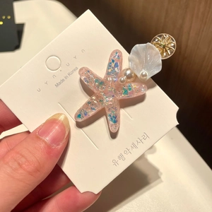 Detailed view of pink starfish hair clip with resin glitter pearls and shell accents