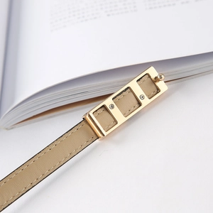 Detail of slim beige leather belt featuring a unique gold three-grid hollow metal buckle