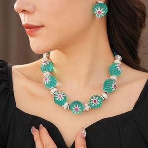Detail view of vintage flower necklace and earring set with green gems worn by a model
