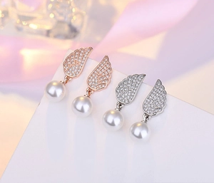 Detailed view of rose gold and silver wing earrings with sparkling cubic zirconia and pearls