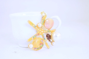 Close-up of golden starfish and shell keychain with rhinestones and white pearls