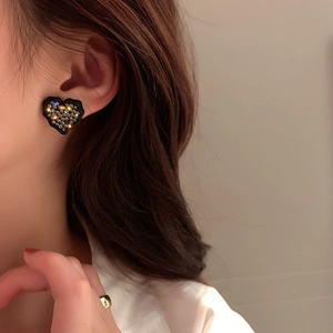 Gros plan de boucles d'oreilles cœur noir avec strass portées par un mannequin