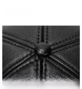 Macro view of a black PU leather winter cap crown showing stitching and center button