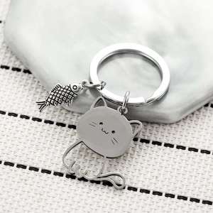 Cute stainless steel cat and fishbone keychain on natural marble stone background