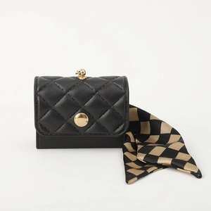 Detail of black quilted mini coin purse with skull charm and checkered silk scarf