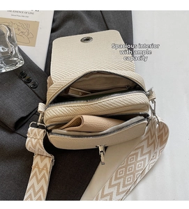 Close-up of beige woven crossbody bag showing three-layer zipper structure and wide strap