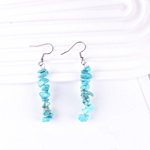 Detailed macro view of long handmade drop earrings featuring irregular turquoise beads