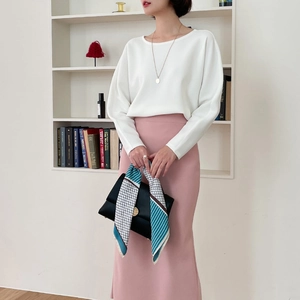 Elegant woman wearing white top and pink skirt with printed silk scarf on handbag