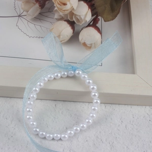 Close-up of girl's faux pearl bracelet featuring a light blue sheer ribbon bow detail