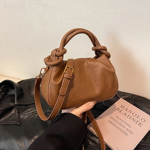Borsa a tracolla in pelle marrone con catena su giacca nera e libro di moda