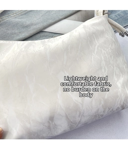 Detail of white tote bag showing unique marble-textured fabric and silver metal hardware