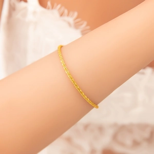 Detailed view of an 18K gold plated stainless steel bracelet with woven texture on a wrist