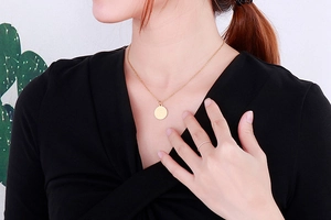 Détail du collier doré avec pendentif pièce ronde et chaîne en O sur le mannequin