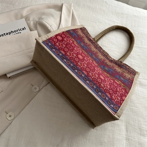 Ethnic jute tote bag with retro elephant prints and woven handles in a side view