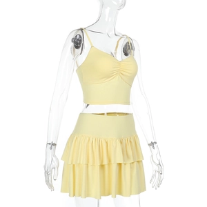 Detail view of yellow two-piece summer set with camisole crop top and pleated tiered skirt
