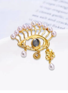 Detailed macro view of Evil Eye brooch with pink pearls, crystals and gold pendants