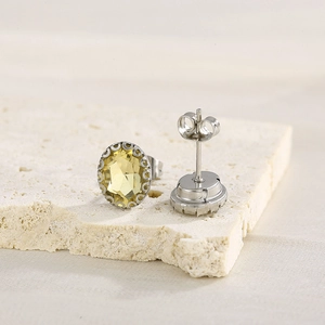 Macro detail of yellow oval rhinestone earrings with silver prong setting and butterfly back