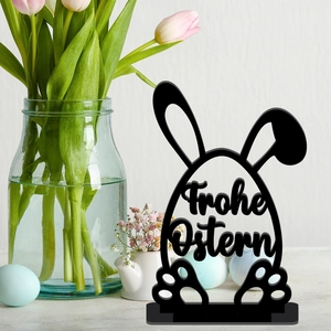 Close-up of black acrylic Easter egg stand with bunny ears and Frohe Ostern text