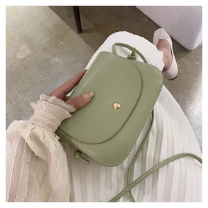 Pale green crossbody bag in matte leather worn with a white pleated skirt for a fresh look