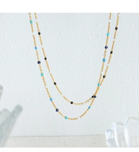 Detail of a gold double-layer chain necklace with colorful black white and blue enamel beads