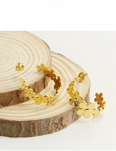 Detailed view of 18K gold-plated stainless steel daisy C-hoop earrings on wood block