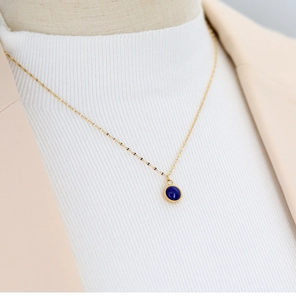 Minimalist 18K gold plated necklace with blue agate pendant on female model outfit