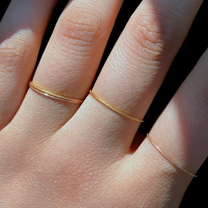 Three-color thin sandblasted stackable rings in 18K gold plating on female hand