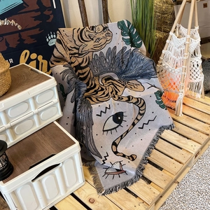 Detail of bohemian woven cotton blanket featuring tiger and leaf patterns with tassel edge
