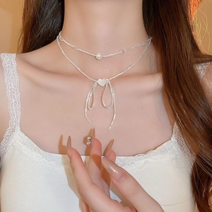 Close-up of double-layer faux pearl necklace with heart and bow detail on collarbone